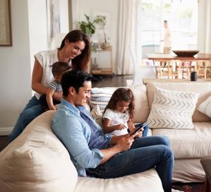 a family studying a tablet on a white living room couch